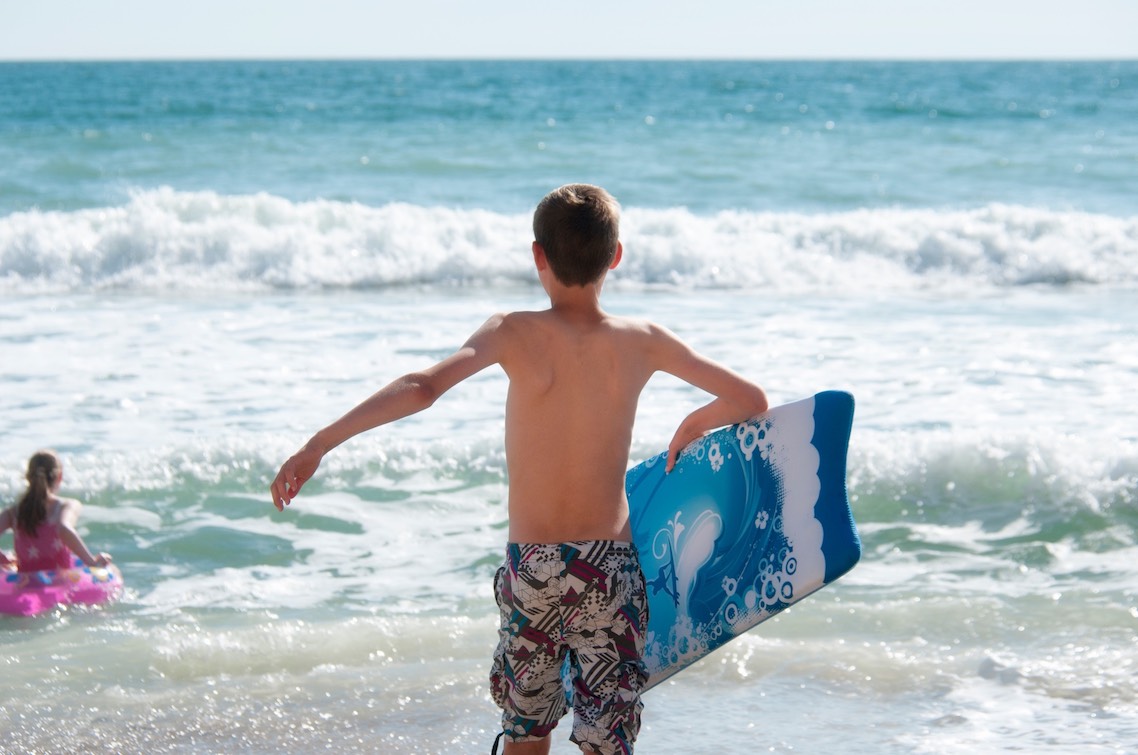 A boy with a bodyboard running into the sea
