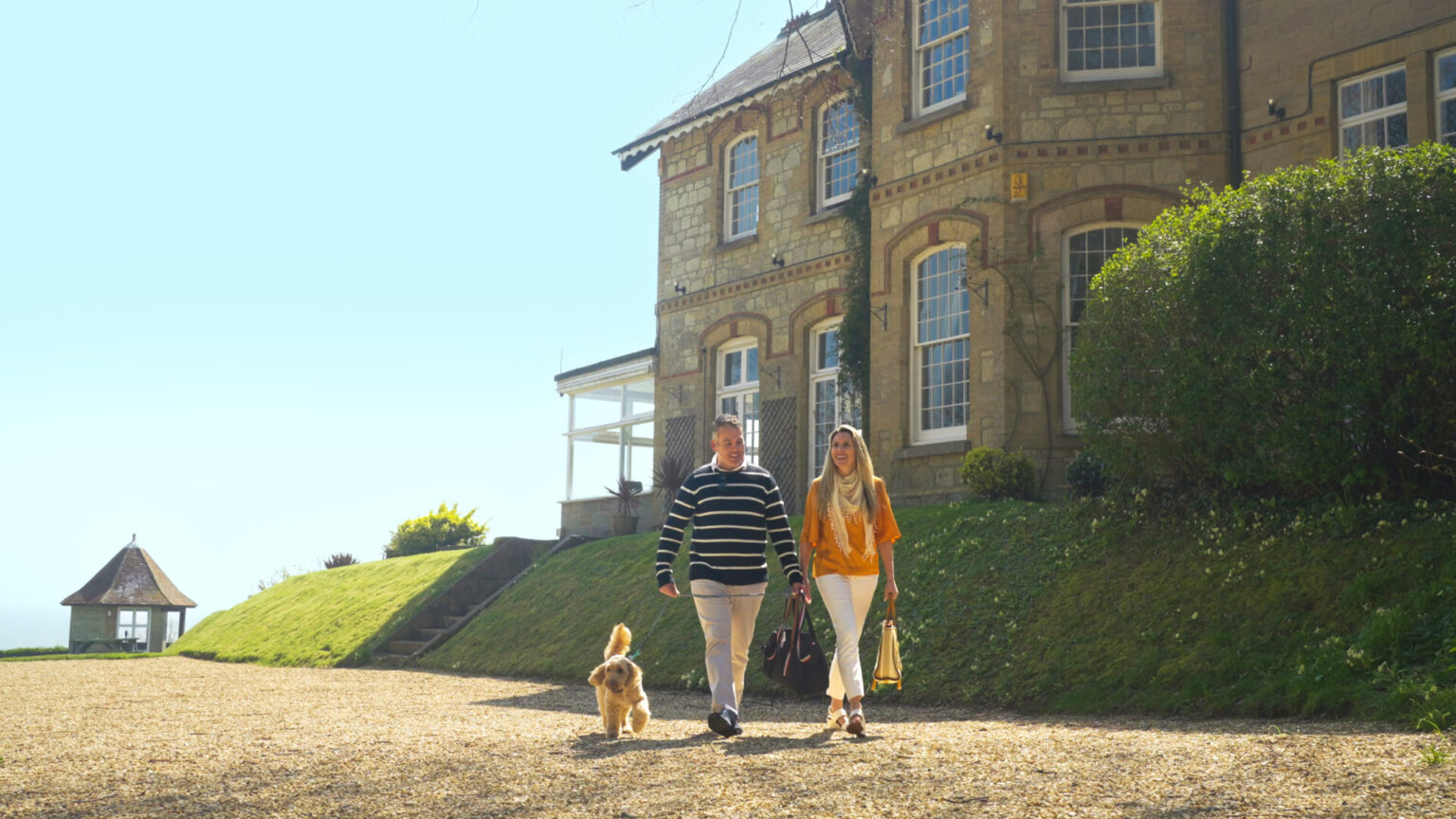 Guests walking their dog on the lawn in front of Luccombe Manor